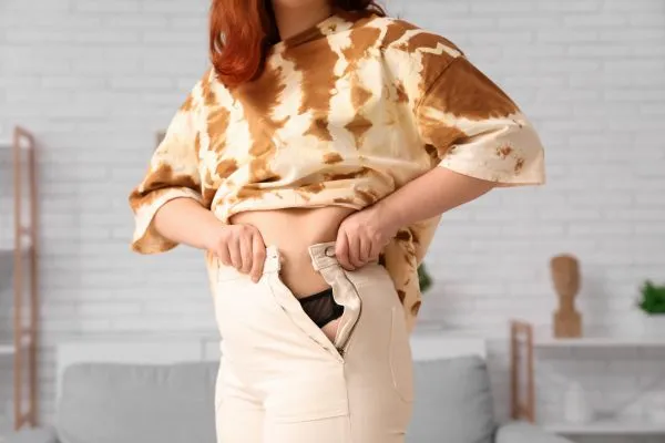 Image of woman trying to do her trousers up after pregnancy weight gain Skegness